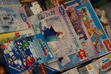 Bunte Spiele- und Puzzleschachteln mit Motiven aus „Frozen“ und „PJ Masks“ auf einem Tisch.