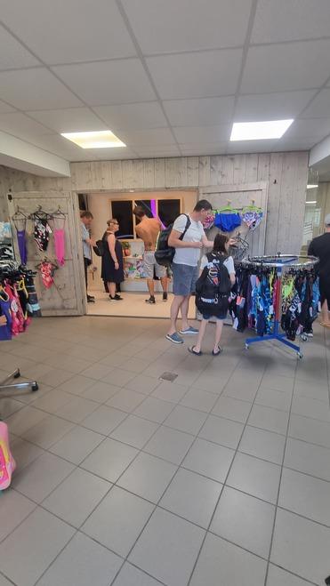 Ein Verkaufsraum mit mehreren Personen, die Badebekleidung an Verkaufsständern betrachten.