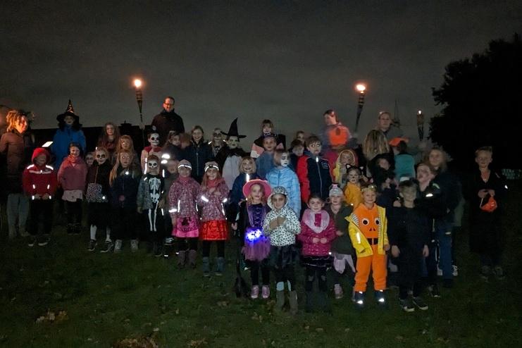 Gruppe von Kindern in Kostümen auf einer Wiese, umgeben von Fackeln, bei nächtlicher Atmosphäre.