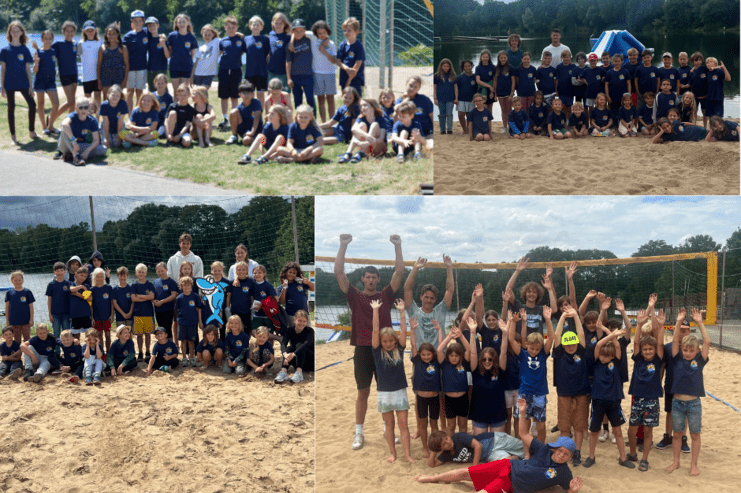 Gruppenfoto von Kindern in blauen T-Shirts am Strand, mit Spielgeräten und Bäumen im Hintergrund.