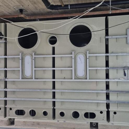 Blick auf eine große, beige Maschinenkomponente mit runden Öffnungen und Metallstreben zur Verstärkung.