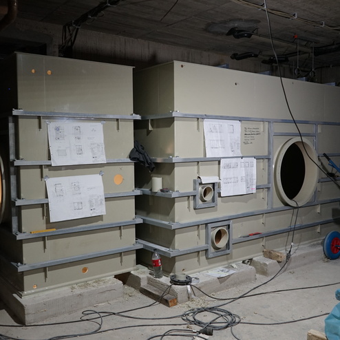 Maschinenanordnung mit Pl&auml;nen und Rohren in einem Baustellenraum, umgeben von Kabeln und einem CO2-Tank.