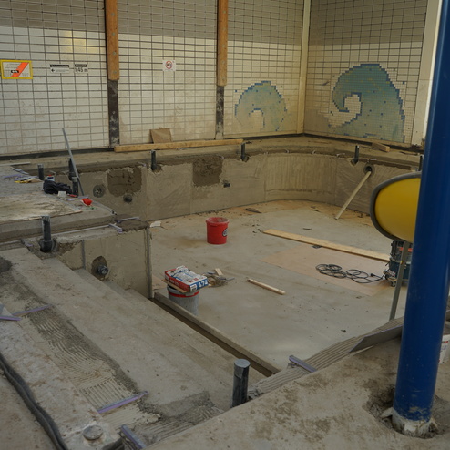 Umbau eines Schwimmbeckens mit Betonarbeiten und Werkzeugen in einem lichtdurchfluteten Raum.