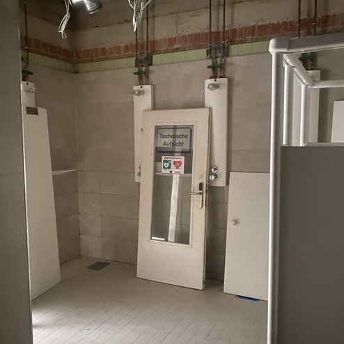 Leerer, grauer Raum mit einer T&uuml;r, auf der ein Schild mit &bdquo;Technische Aussicht&ldquo; angebracht ist.