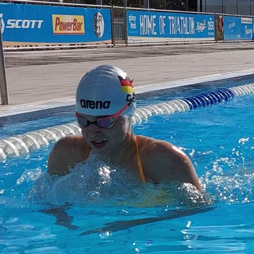 Schwimmerin in einem blauen Schwimmbecken, mit Kappe und Brille, schwimmt intensiver Ausdruck während des Trainings.