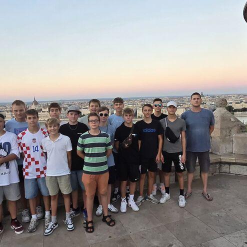 Gruppe von Jugendlichen und Erwachsenen posiert vor einem historischen Gebäude mit Blick auf die Stadt und den Fluss.