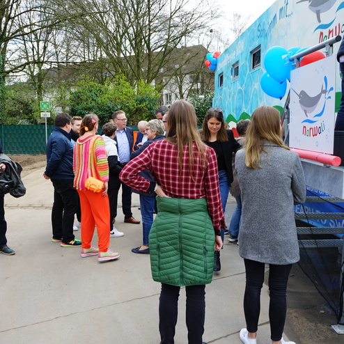 Gruppe von Personen, die sich vor einem bunten Fahrzeug mit Seehundmotiv in einem Park versammelt.