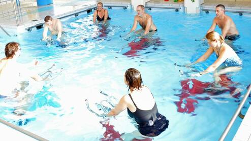 Drei Damen und dreien Herren machen Aqua-Cycling im Schwimmbecken