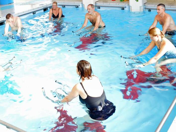 Drei Damen und dreien Herren machen Aqua-Cycling im Schwimmbecken