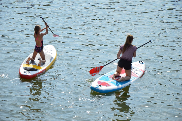 Zwei Mädels knien auf einem SUP-Board im Wasser