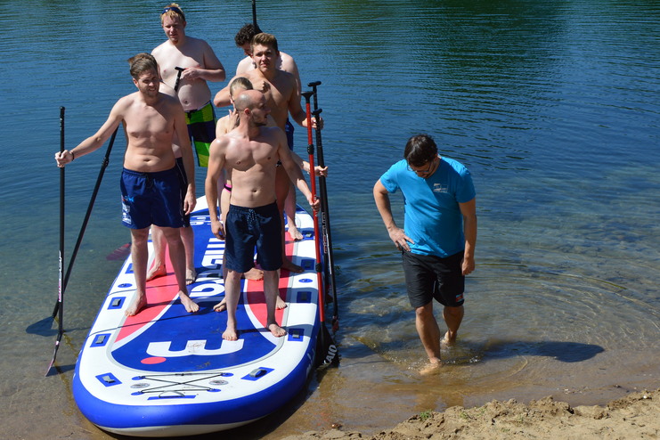 Eine Gruppe von 8 Leuten stehen auf einem SUP-Board