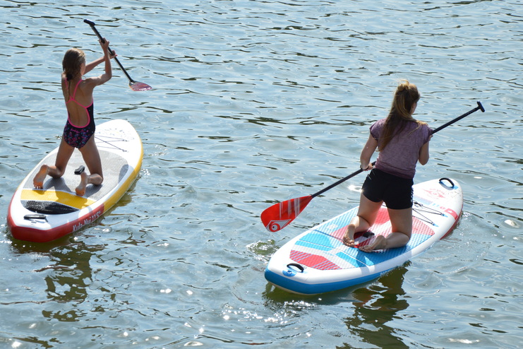 Zwei Mädels knien auf einem SUP-Board im Wasser