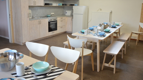 Essbereich mit einem gedeckten Tisch, Stühlen und einer offenen Küche in einem modernen Raum.