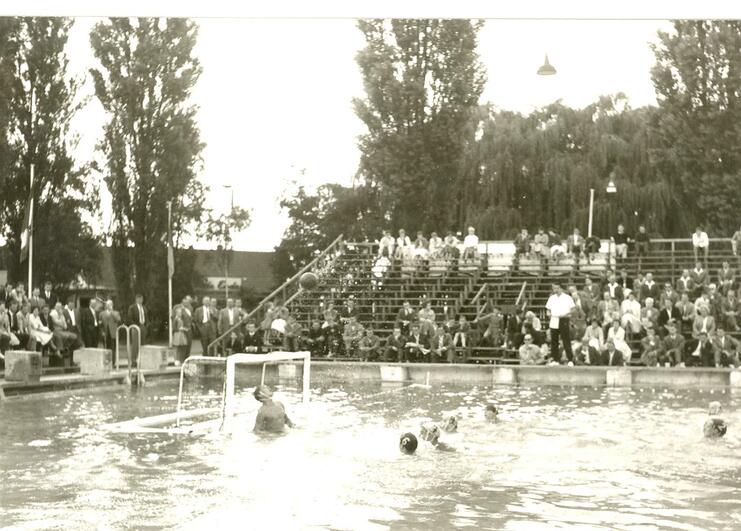 Wasserballspiel im Freien, Zuschauer auf Tribüne beobachten das Geschehen im Wasser. Genießen eines sportlichen Events.