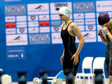 Schwimmerin in schwarzem Wettkampfanzug steht startbereit am Beckenrand während der Deutschen Meisterschaften.