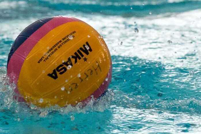 Wasserball rollt auf der Oberfläche eines Schwimmbeckens, umgeben von spritzendem Wasser.