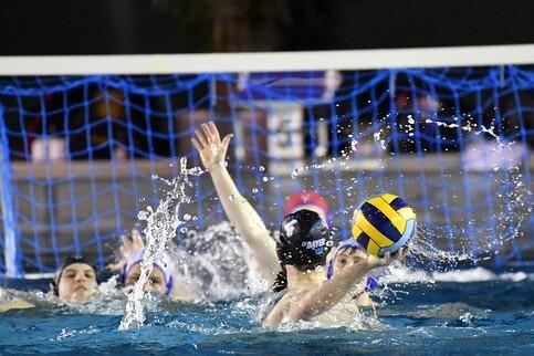 Wasserballspiel mit mehreren Spielerinnen, die um den Ball kämpfen und Spritzer im Wasser erzeugen.