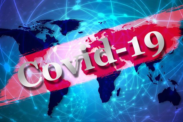 Weltkarte mit dem Schriftzug "Covid-19" in großen, grauen Buchstaben auf rotem Hintergrund.