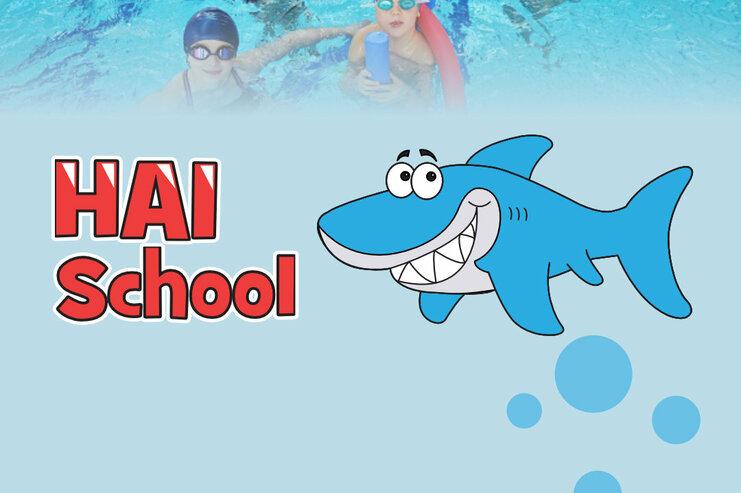 Gruppe von Kindern mit Schwimmbrillen im Wasser, umgeben von Schwimmnudeln, neben dem Schriftzug „HAI School“.