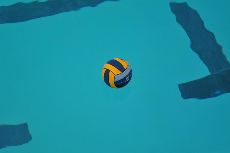 Wasserball schwimmt auf der Oberfläche eines blauen Schwimmbeckens, umgeben von Linienmarkierungen.