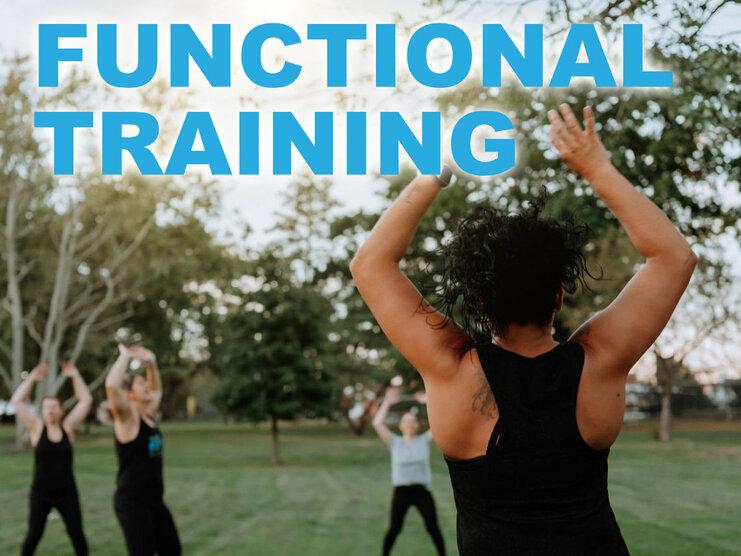 Person leitet eine Gruppe beim Functional Training im Freien auf einer grünen Wiese mit Bäumen im Hintergrund.