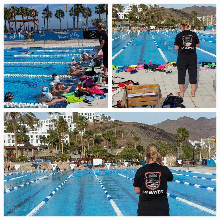 Gruppentraining im Schwimmbecken mit Kindern und Betreuerin, umgeben von Palmen und Bergen im Hintergrund.