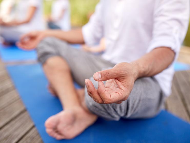 Ein Mann sitzt im Schneidersitz und macht Yoga
