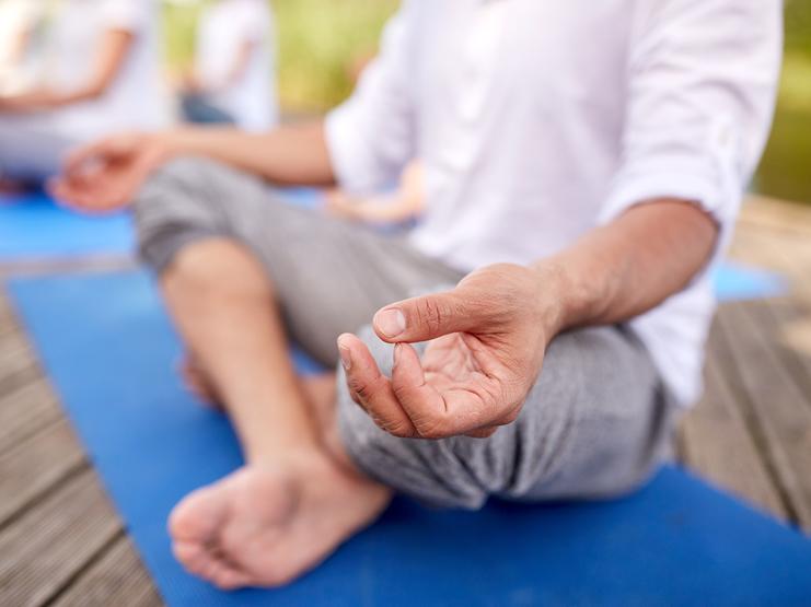 Ein Mann sitzt im Schneidersitz und macht Yoga